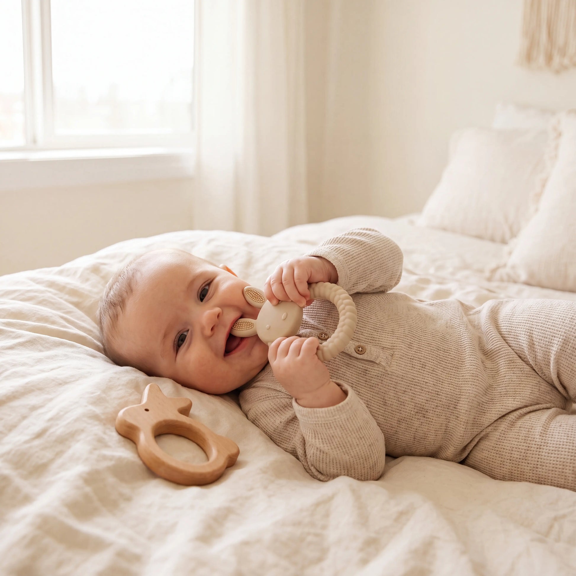 Baby chewing Rahaya bunny teether on cream linen