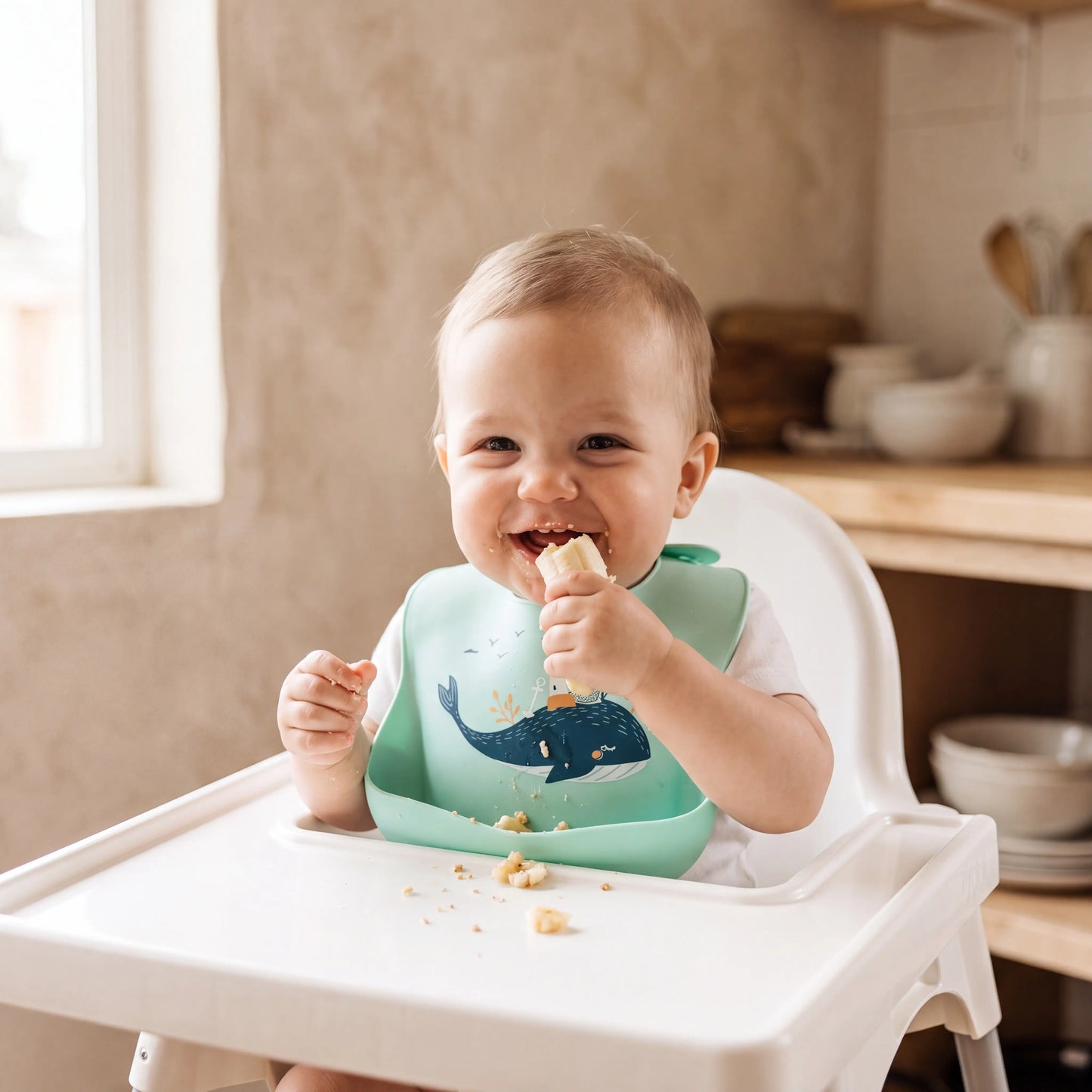Baby wearing Rahaya whale bib eating in high chair