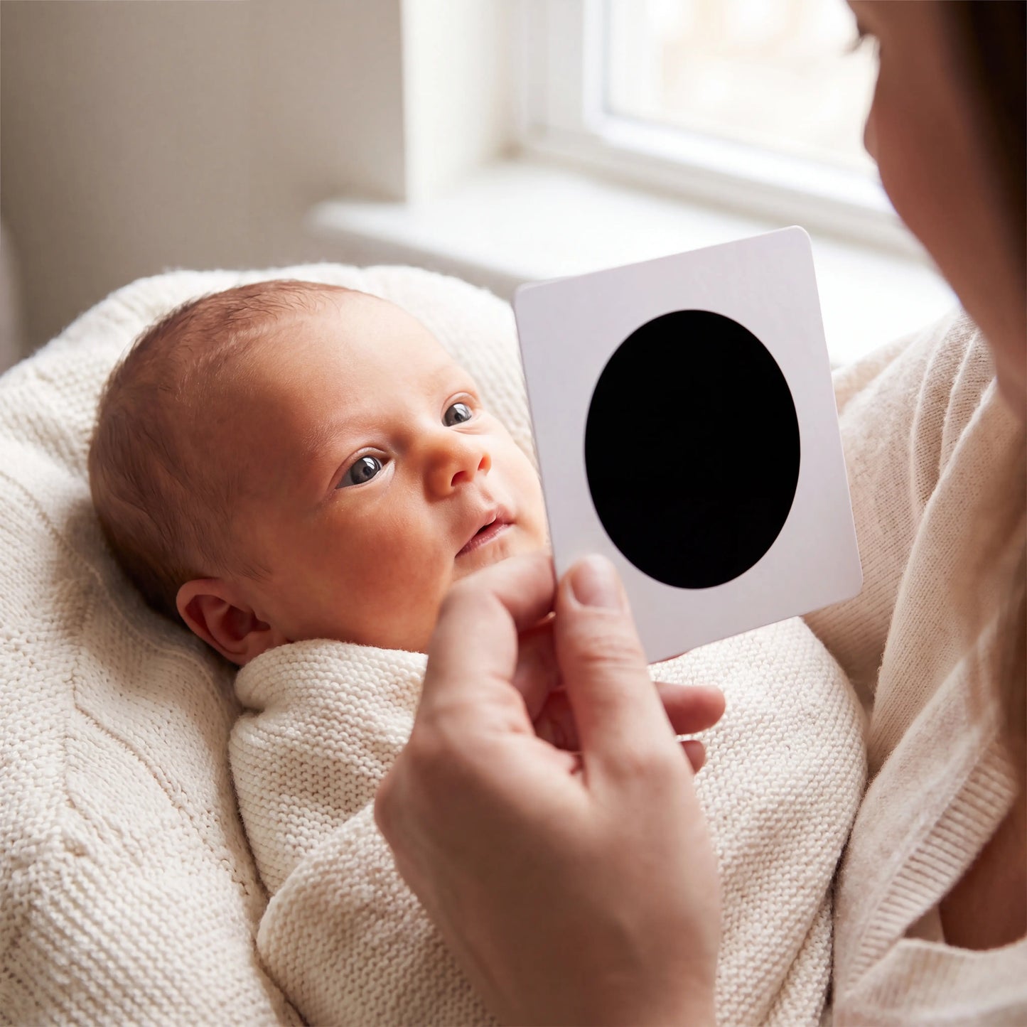 Parent holding Rahaya high-contrast card for newborn